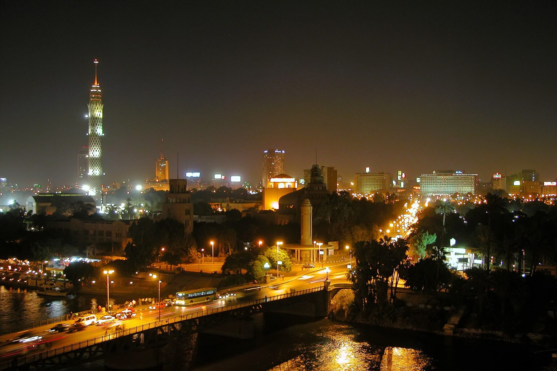Night view over the Nile and central Cairo, with the lit Cairo Tower on the left and a bridge with traffic in the foreground