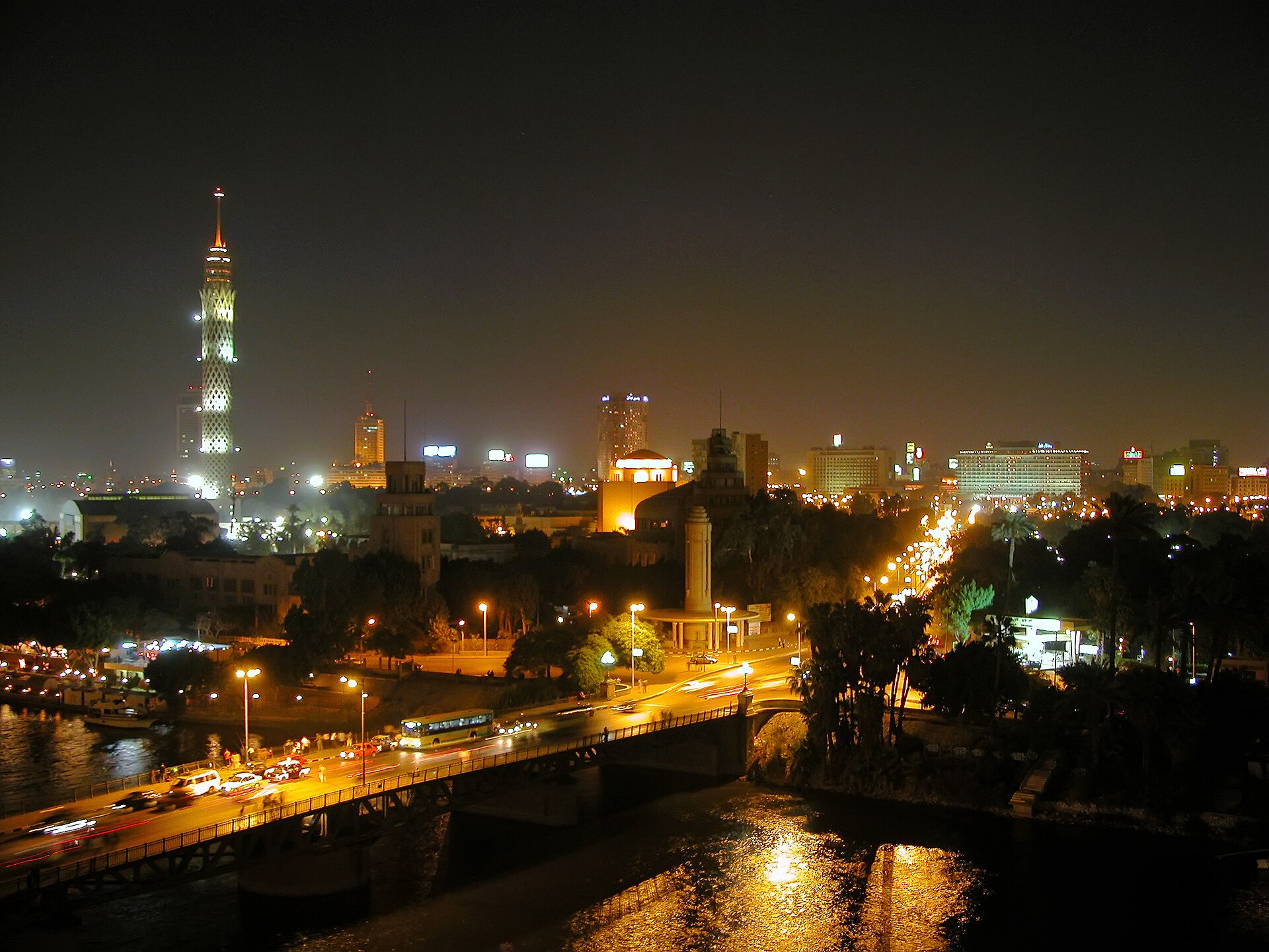 Night view over the Nile and central Cairo, with the lit Cairo Tower on the left and a bridge with traffic in the foreground