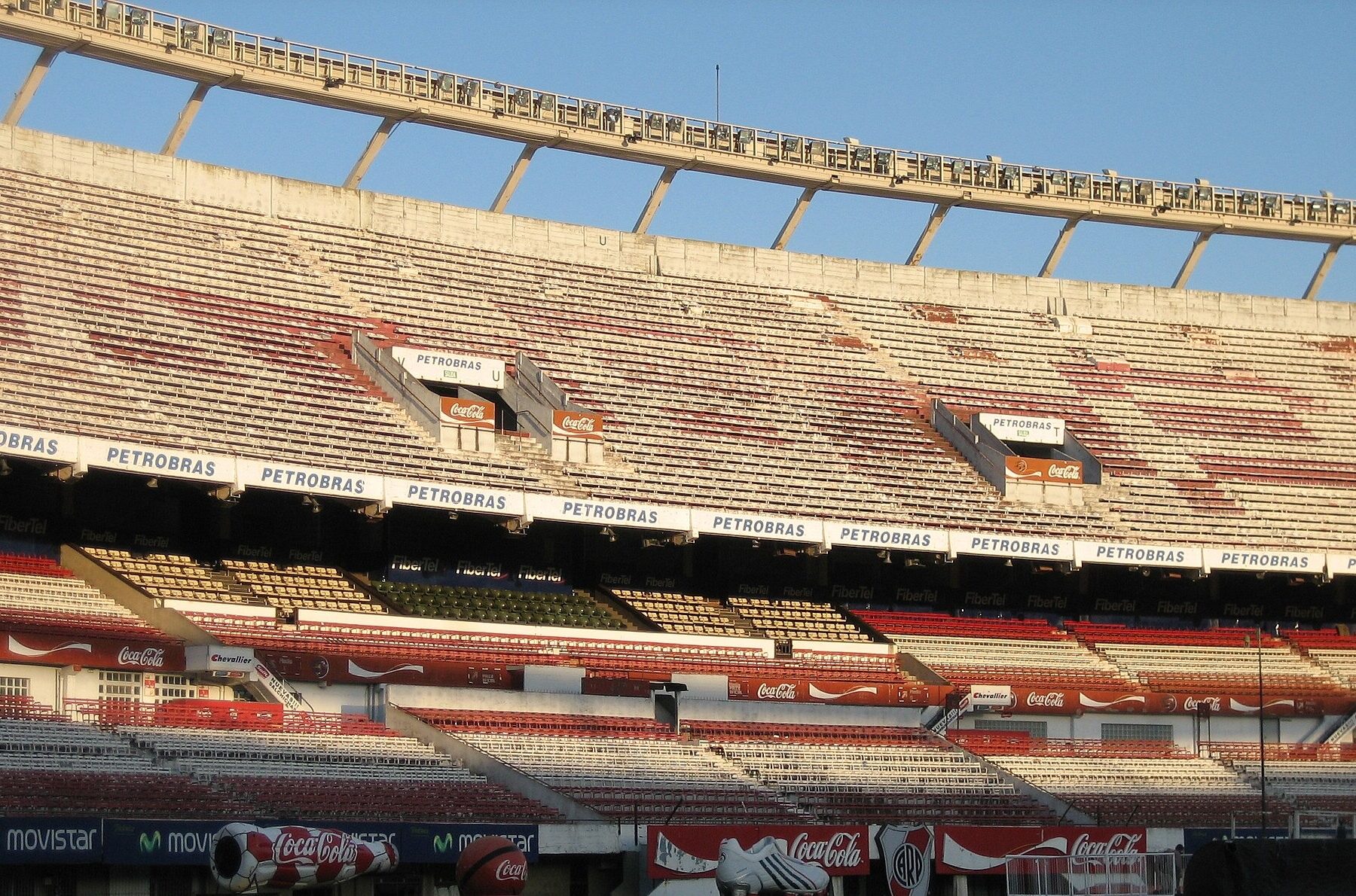 The upper and lower tiers of the stands at Estadio Monumental in Buenos Aires, with Petrobras and Coca-Cola advertising boards and a curved roof edge