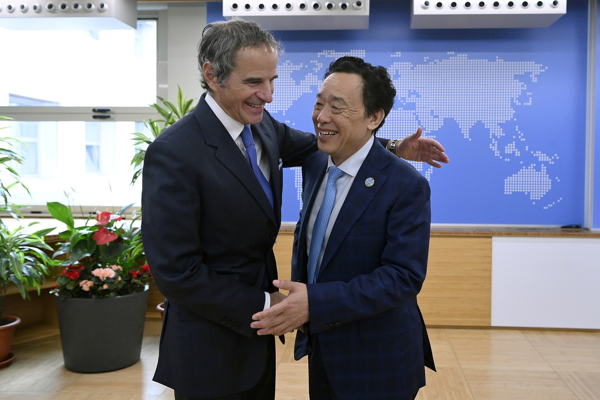 FAO Director-General Qu Dongyu greeting IAEA chief Rafael Mariano Grossi in front of a world map wall