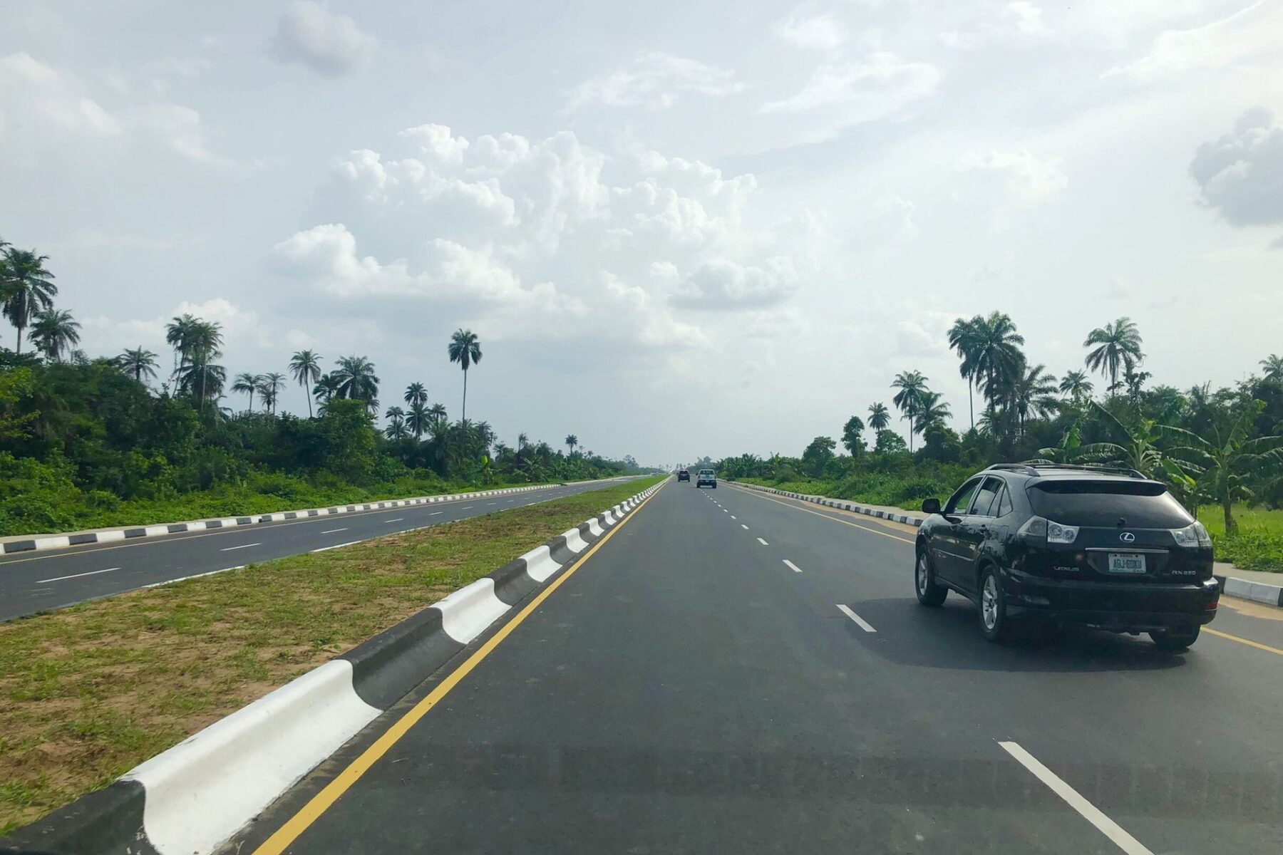 A divided bypass road lined with palm trees in Yenagoa, Bayelsa State, Nigeria